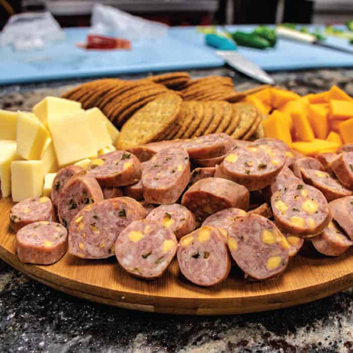 Hofmann Jalapeño Cheddar Sausage on a tray with cheese and crackers